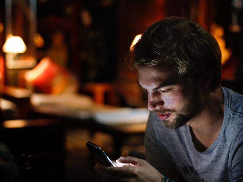 Man using cell phone in dimly lit office