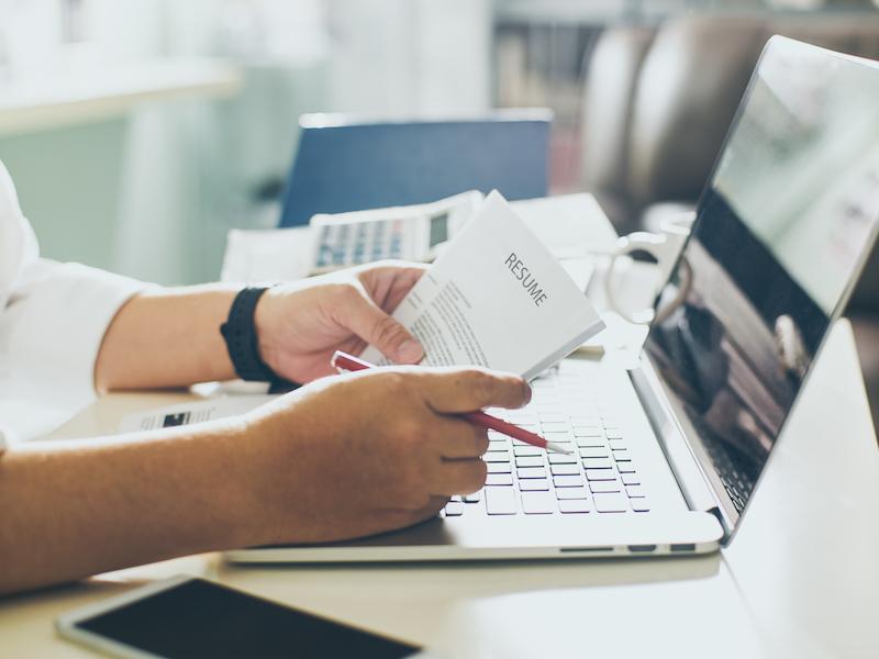 Person reading papers in front of laptop screen