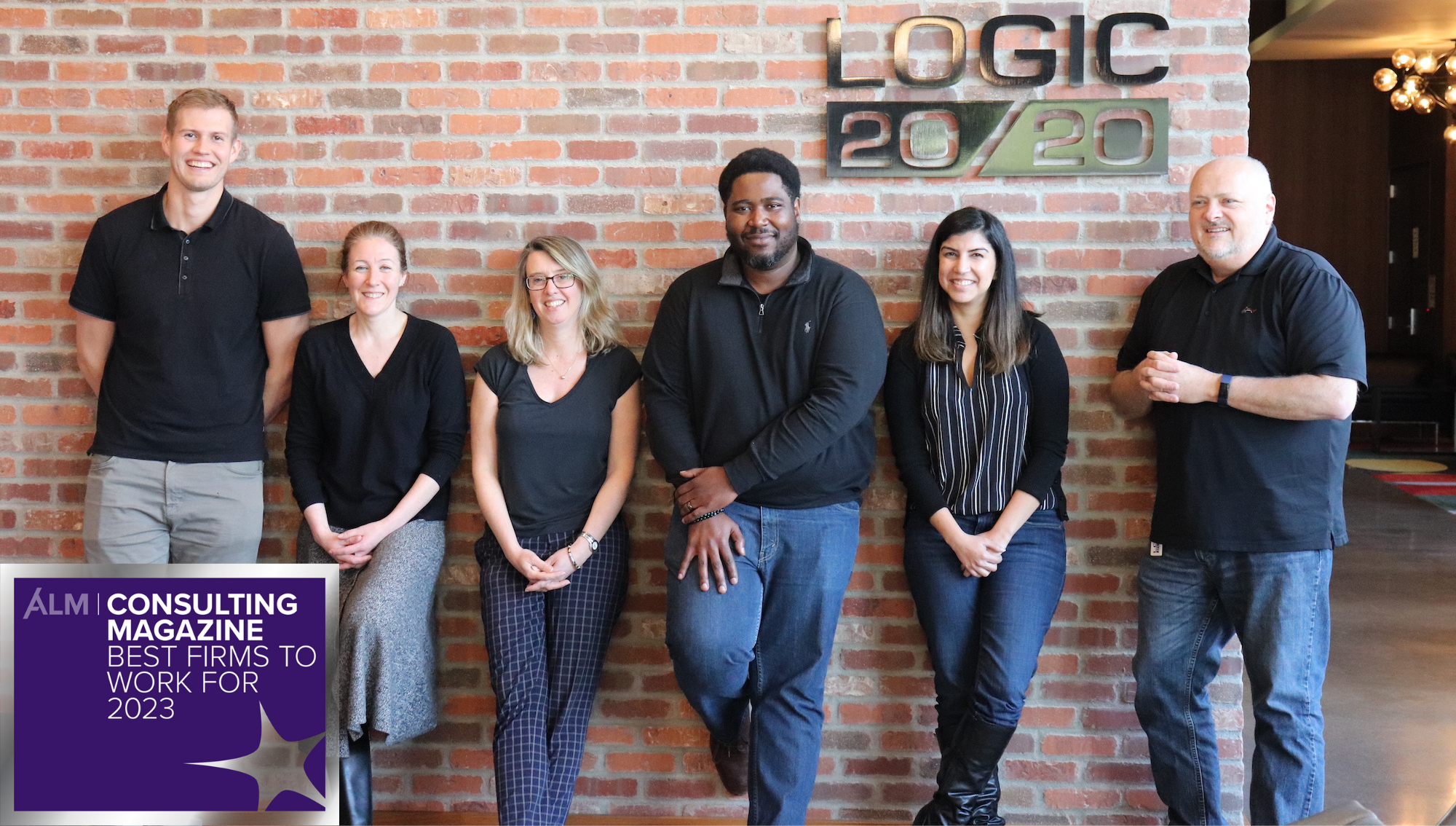 Logic20/20 team members pose in front of our lobby sign