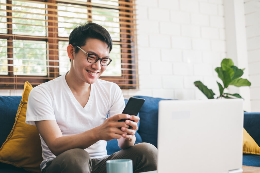 man smiling at phone and laptop