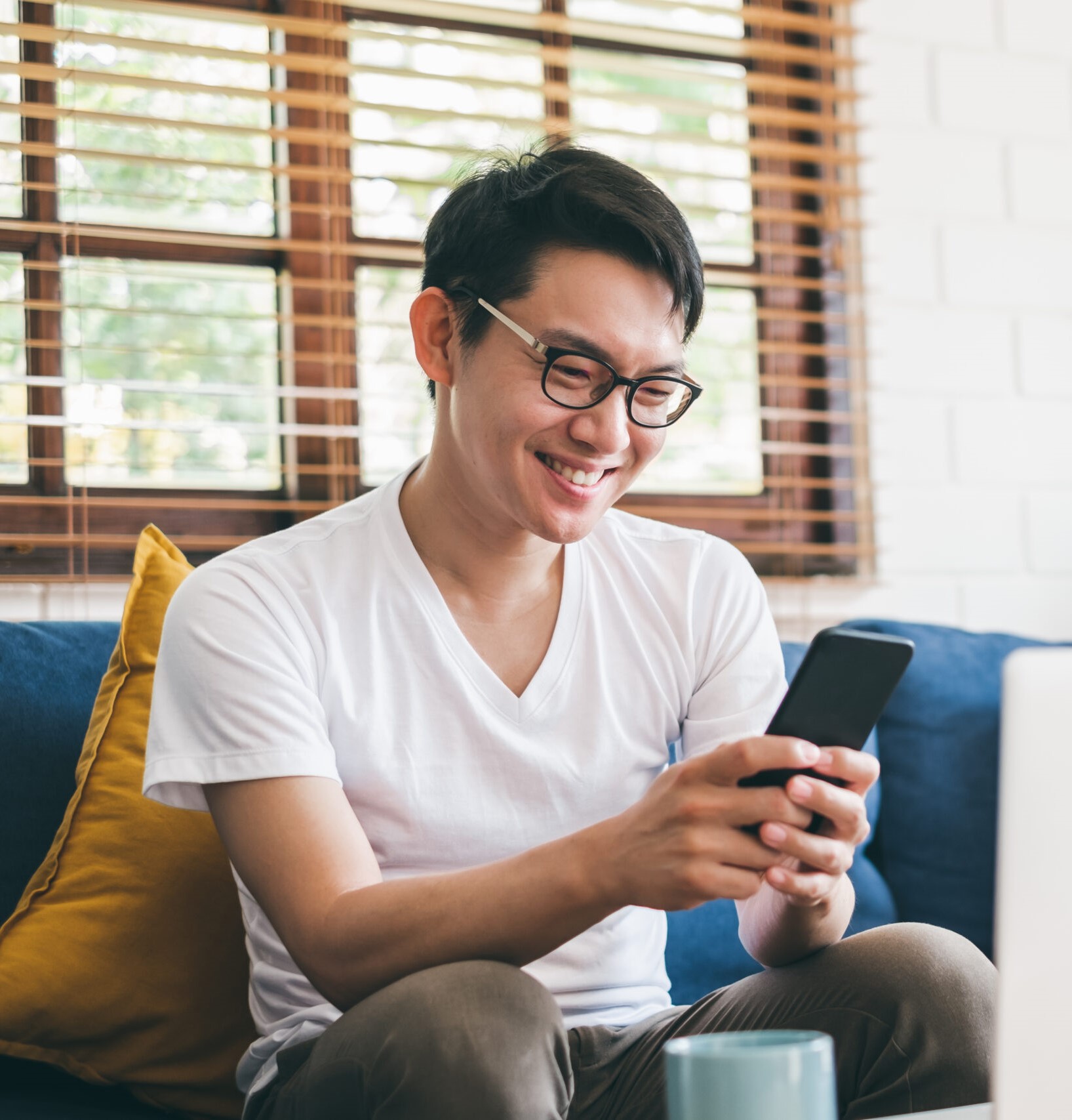 man smiling at phone and laptop