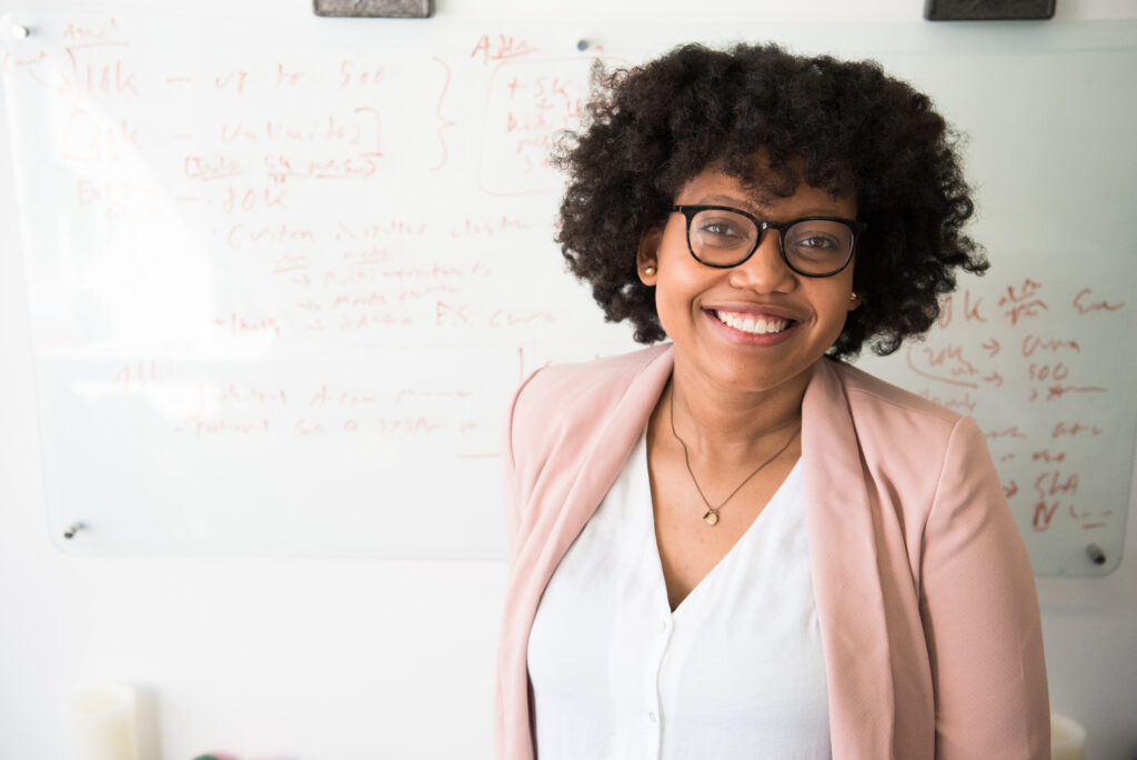 smiling woman standing in front of a whiteboard