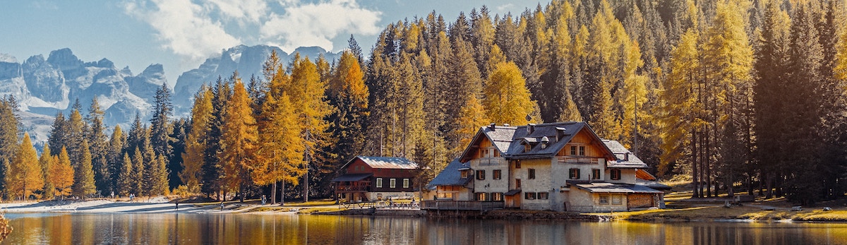house on a lake surrounded by trees and mountains