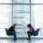 make-software-adoptions-stick-with-change-management-banner two women against a glass wall in an office environment working on laptop computers