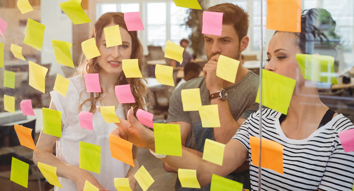 team arranging sticky notes on a glass wall in an office setting