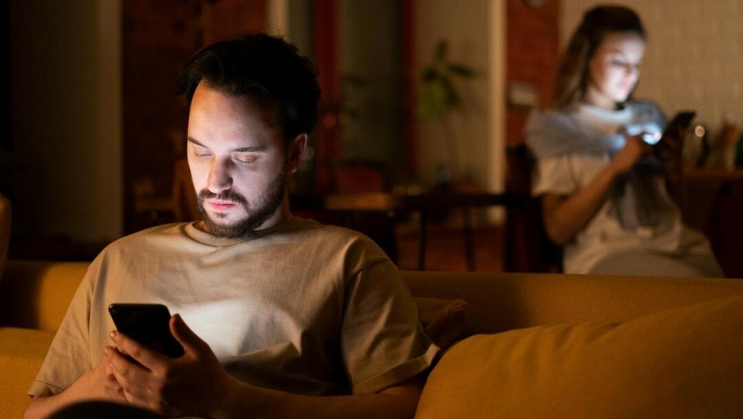 people in a darkened home on their smartphones