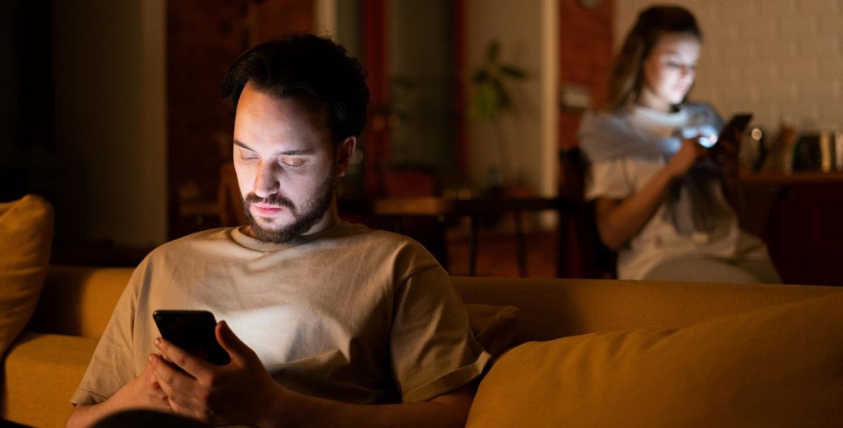 people in a darkened home on their smartphones