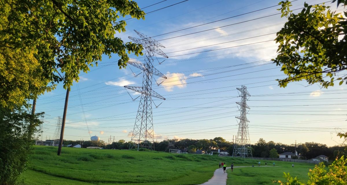 power lines against a sunny sky in a green area