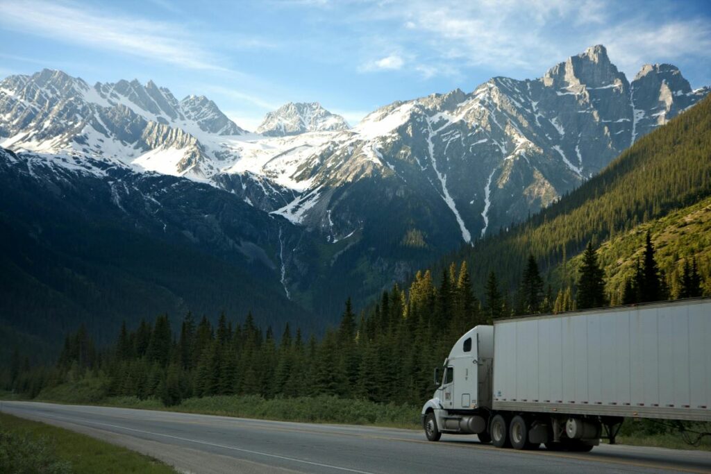 Semi truck driving through a green, mountainous countryside