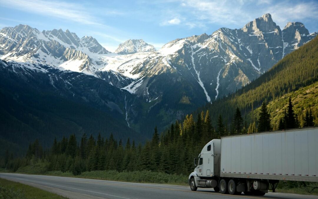 Semi truck driving through a green, mountainous countryside