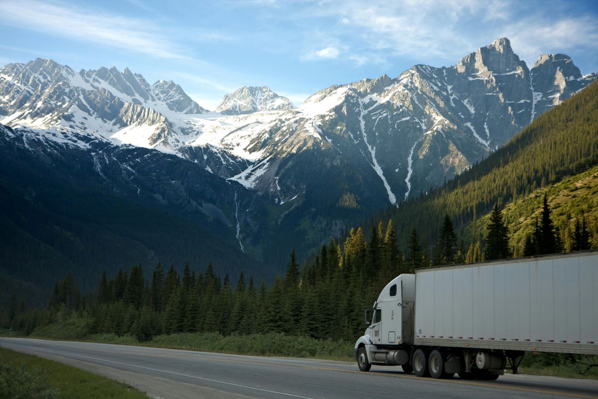 Semi truck driving through a green, mountainous countryside