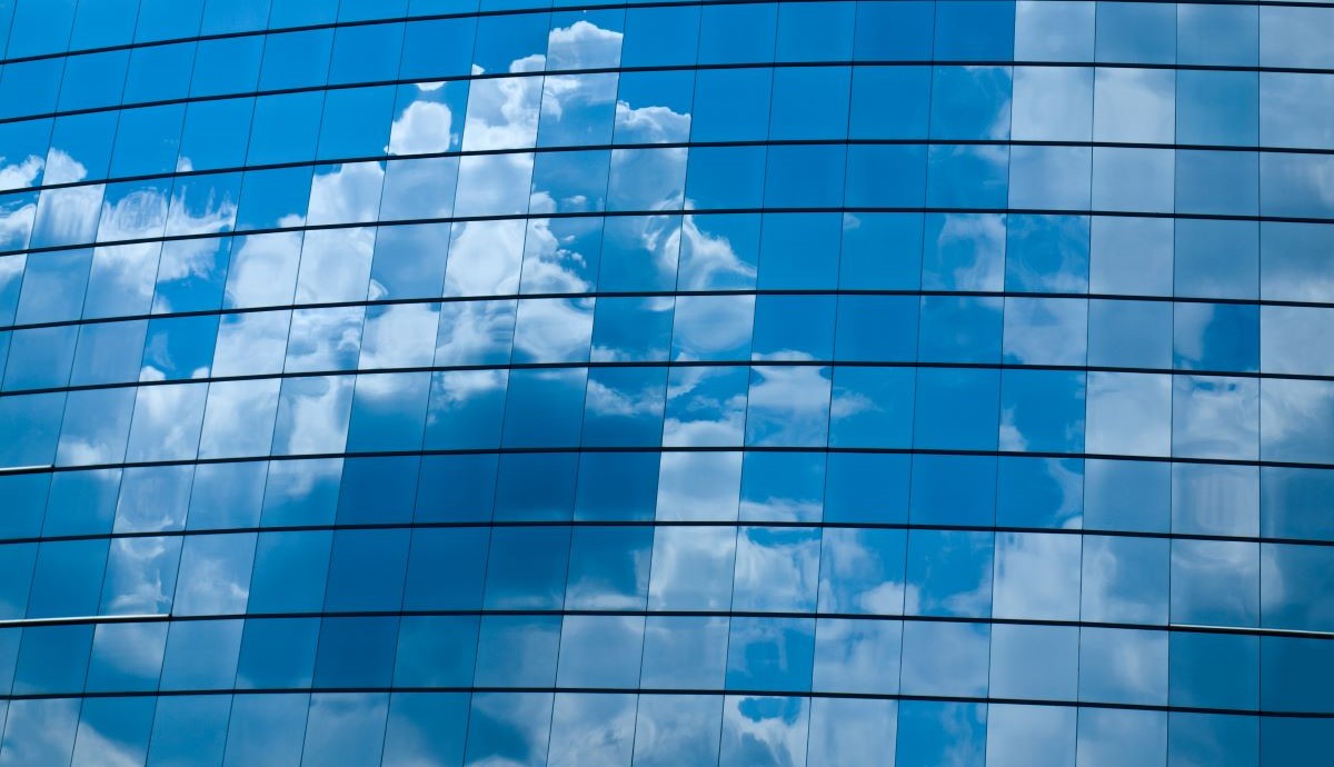 clouds reflected on glass panels of office building