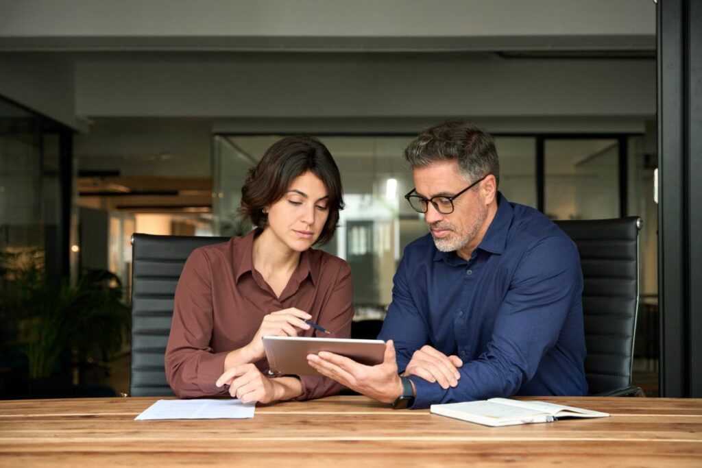 sales rep and client reviewing content on a tablet at a conference room table