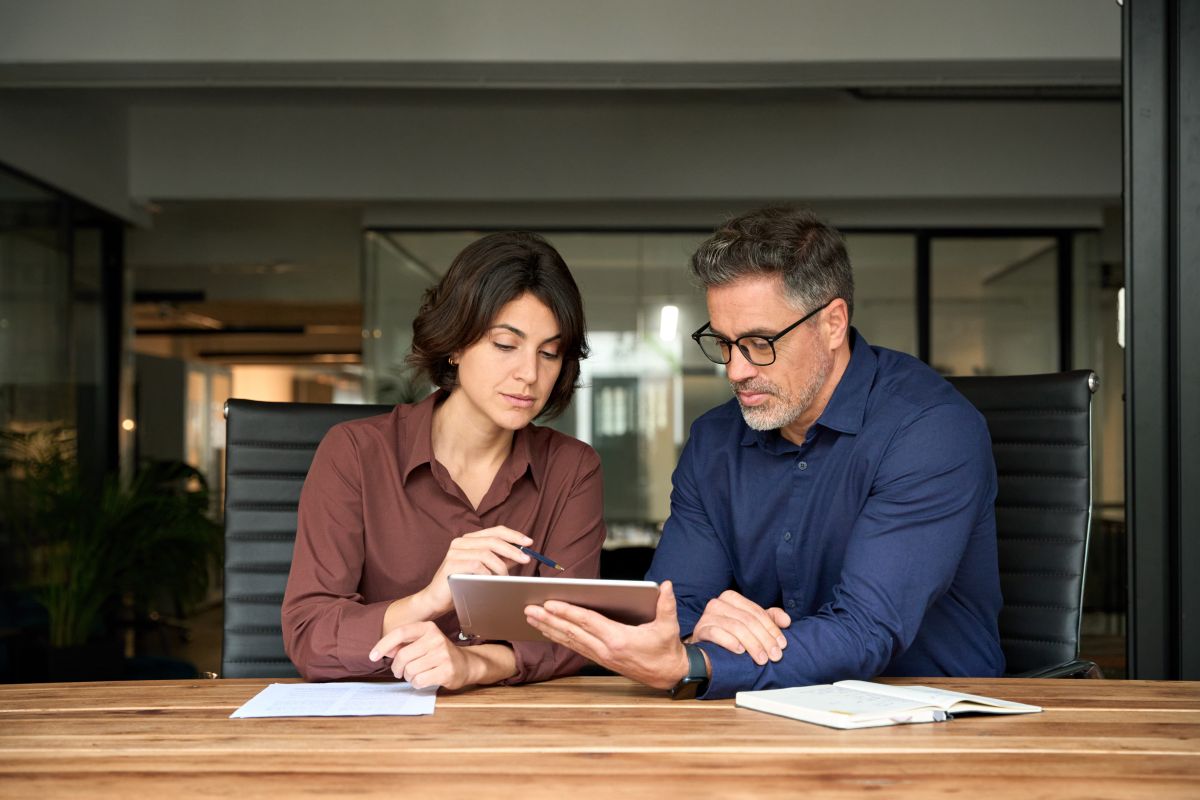 sales rep and client reviewing content on a tablet at a conference room table