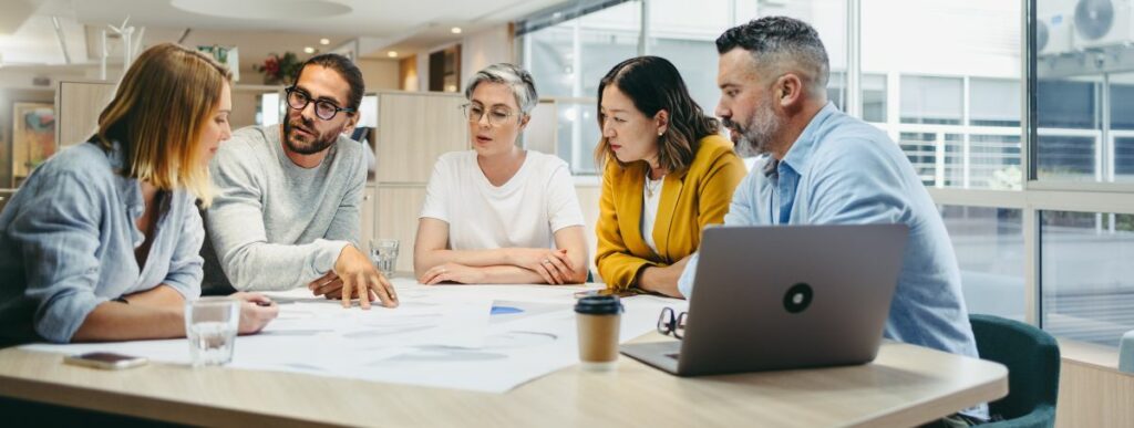 five-person team meeting at a conference table in a modern office setting