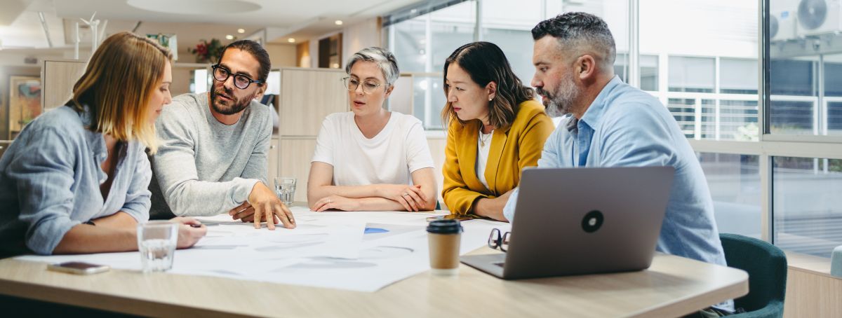 five-person team meeting at a conference table in a modern office setting