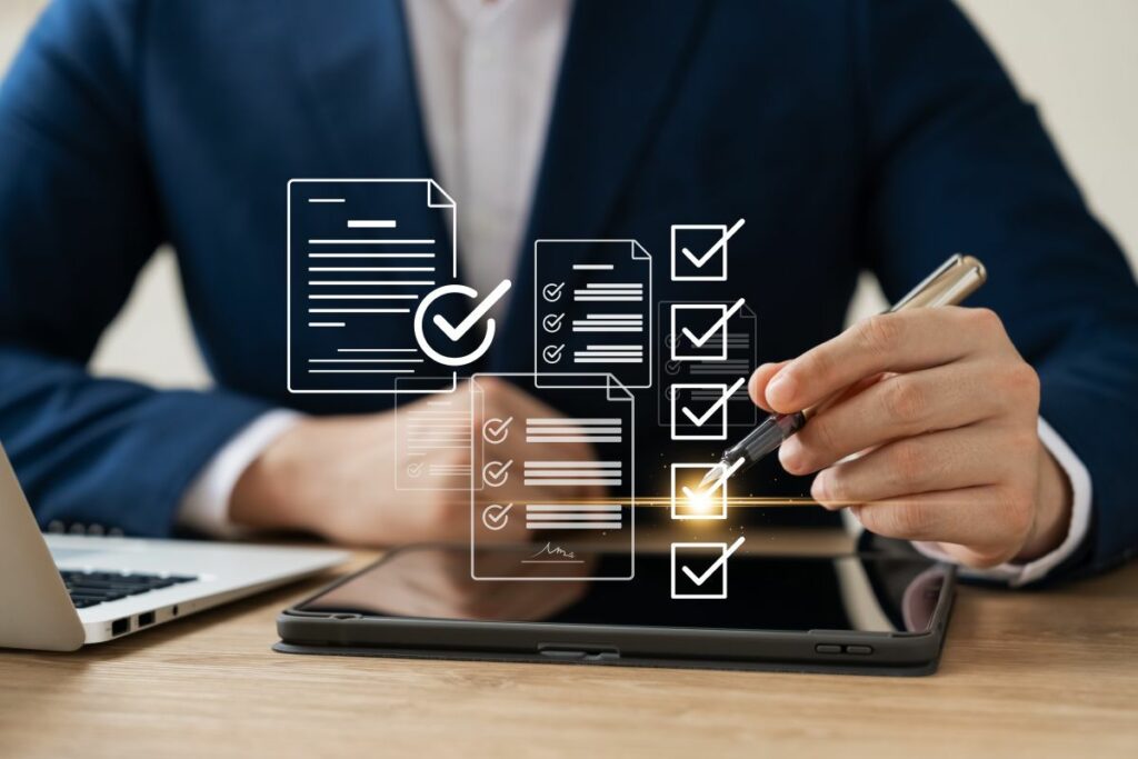 checklist graphics in front of man in suit sitting at a desk with a laptop and tablet