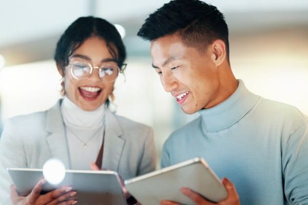 happy coworkers interacting with AI on tablet devices