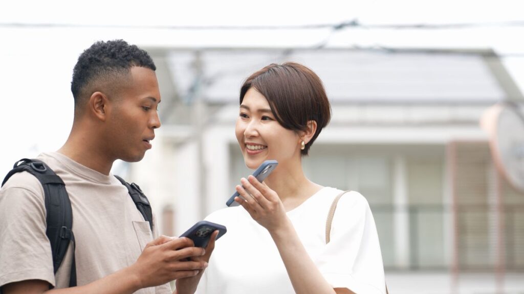 Asian woman showing her smartphone screen to an African American man