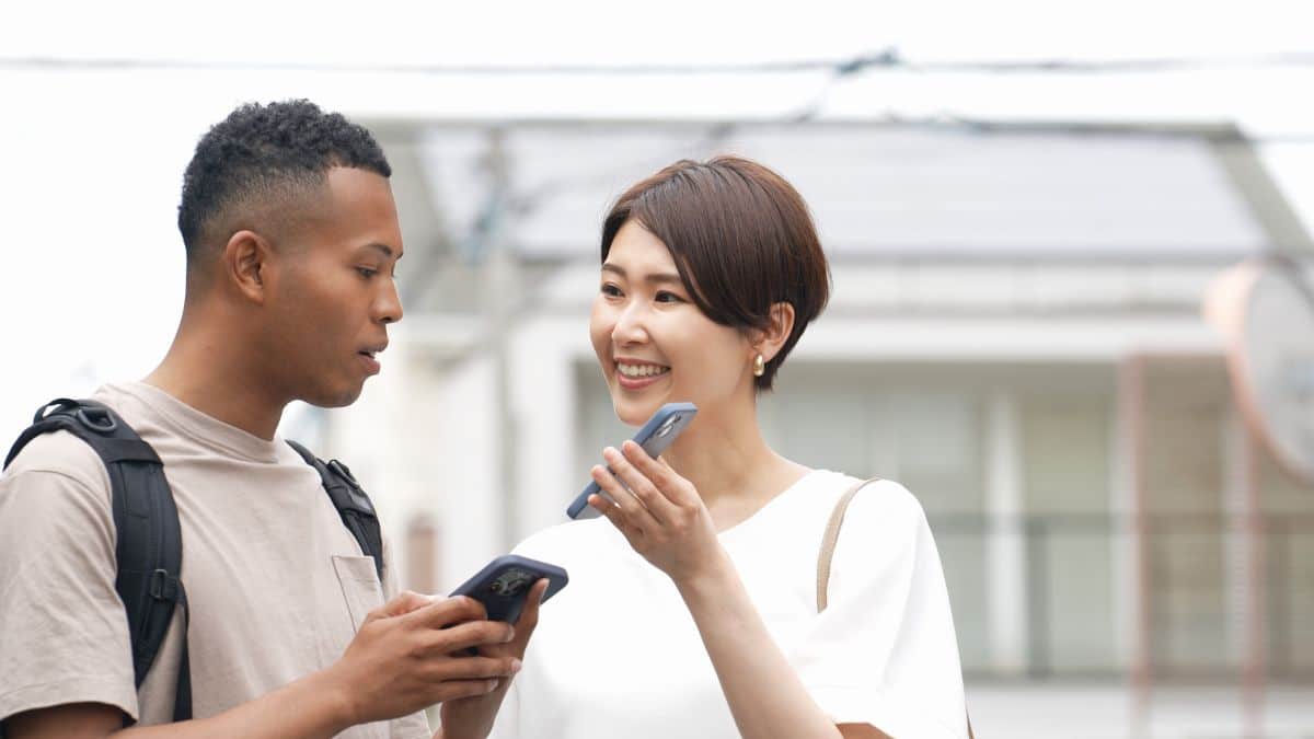 Asian woman showing her smartphone screen to an African American man