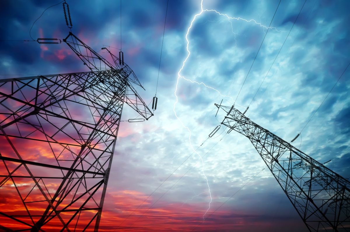 upward-facing view of two utility towers against a lightning-filled sky at dusk