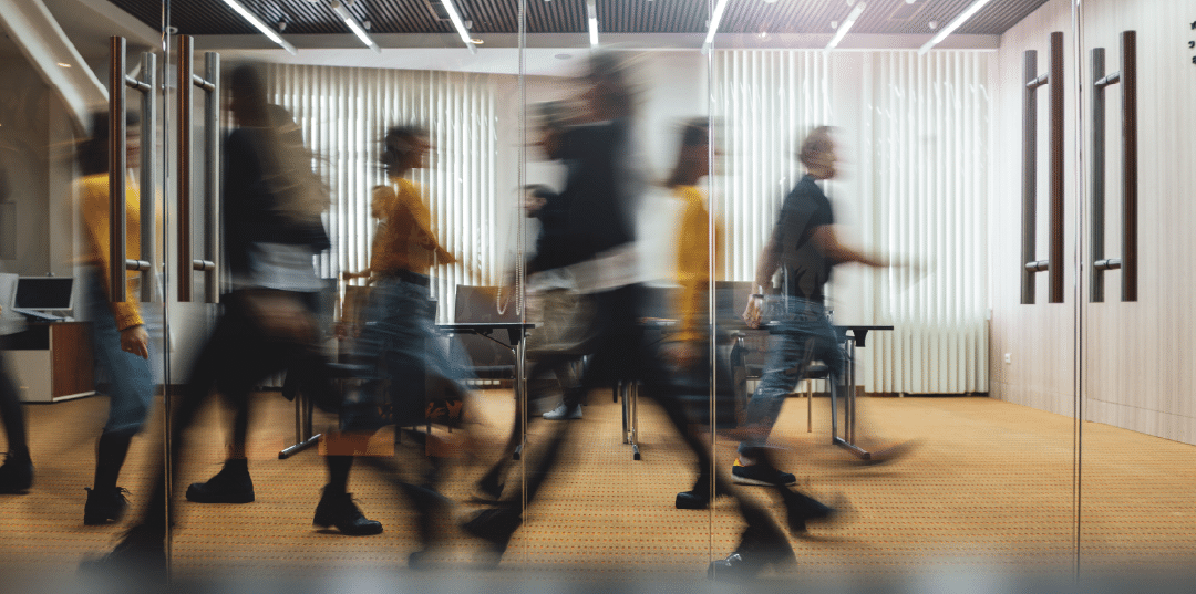 layered photo with blurred people walking across a boardroom