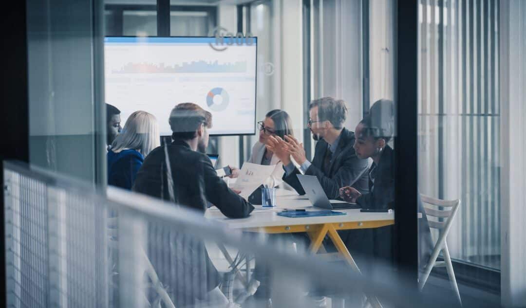 Business professionals meeting in a conference room with analytics displayed on a presentation screen