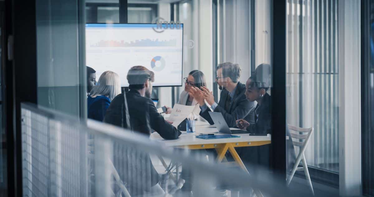 Business professionals meeting in a conference room with analytics displayed on a presentation screen