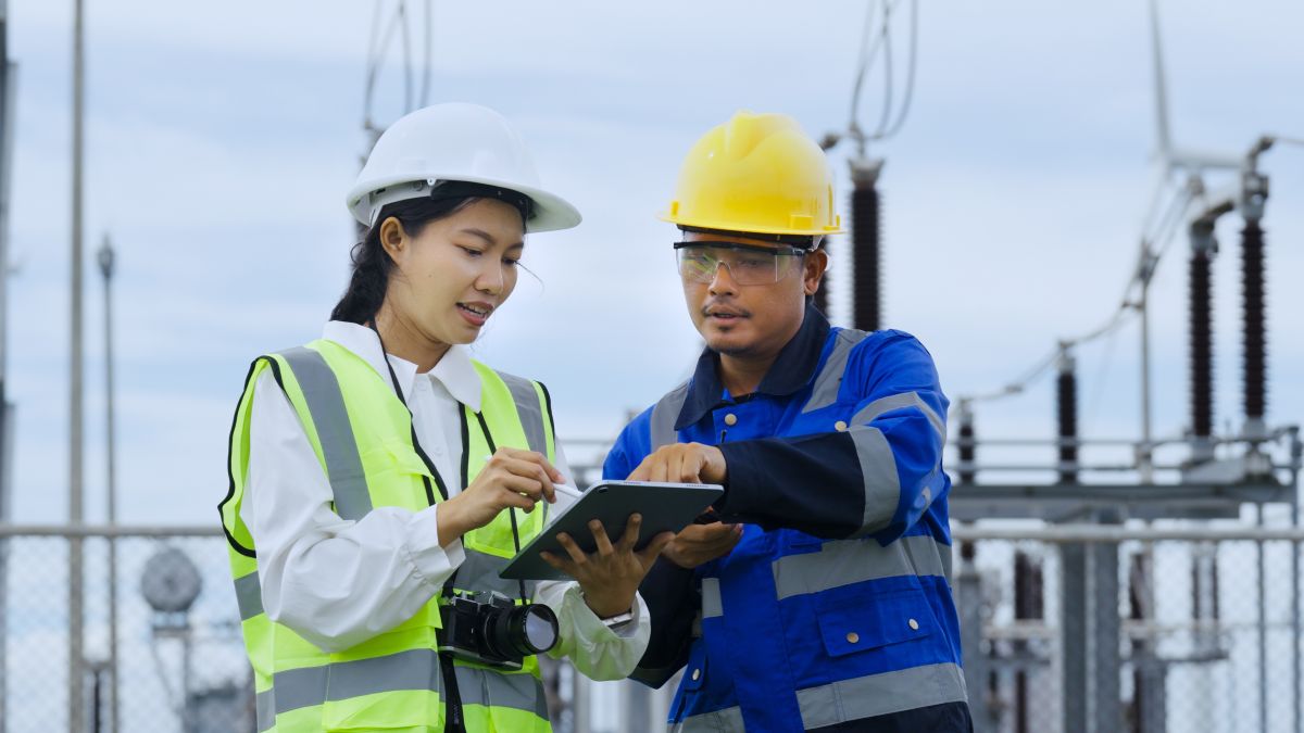 engineers reviewing data on a tablet at an electricity substation