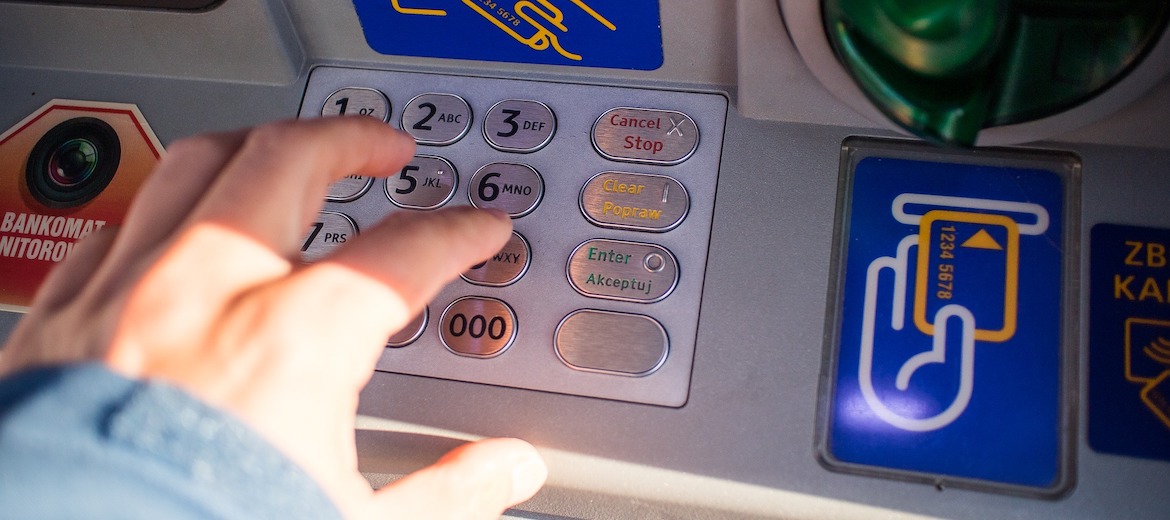 person pressing buttons on Braille ATM keypad